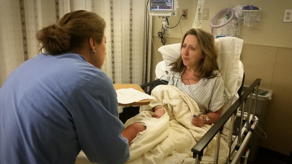 Millennial in hospital has had surgery and the nurse giving her instructions on care at home.